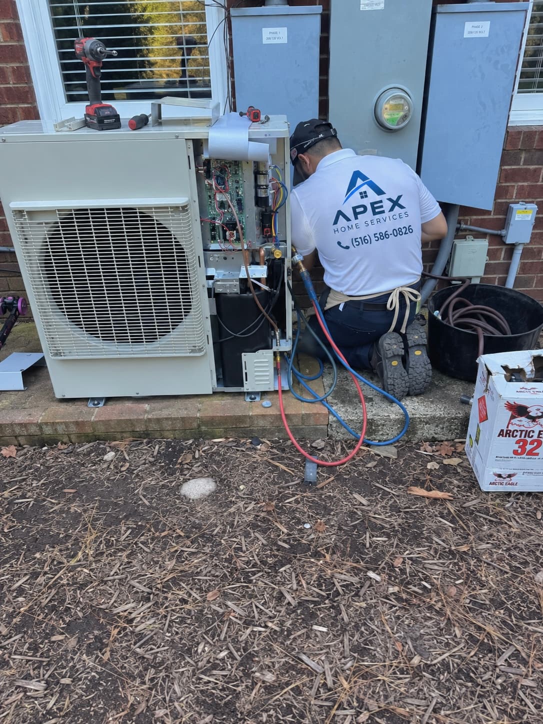Apex technician servicing an outdoor HVAC heating unit with the access panel open