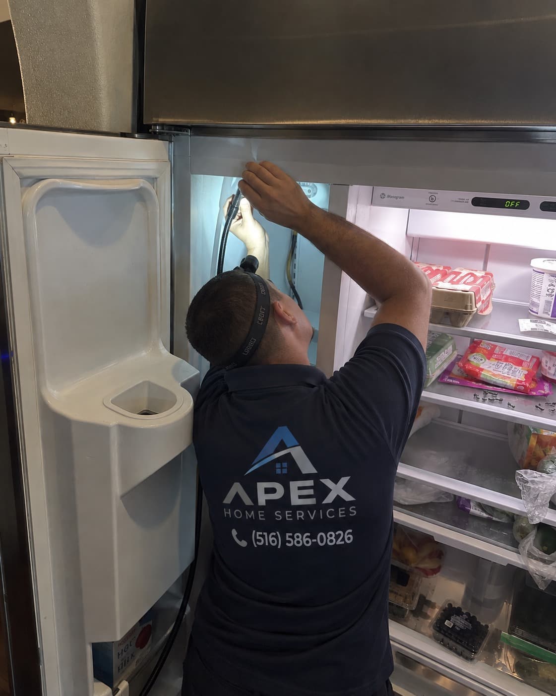 Apex technician working inside an open refrigerator freezer compartment