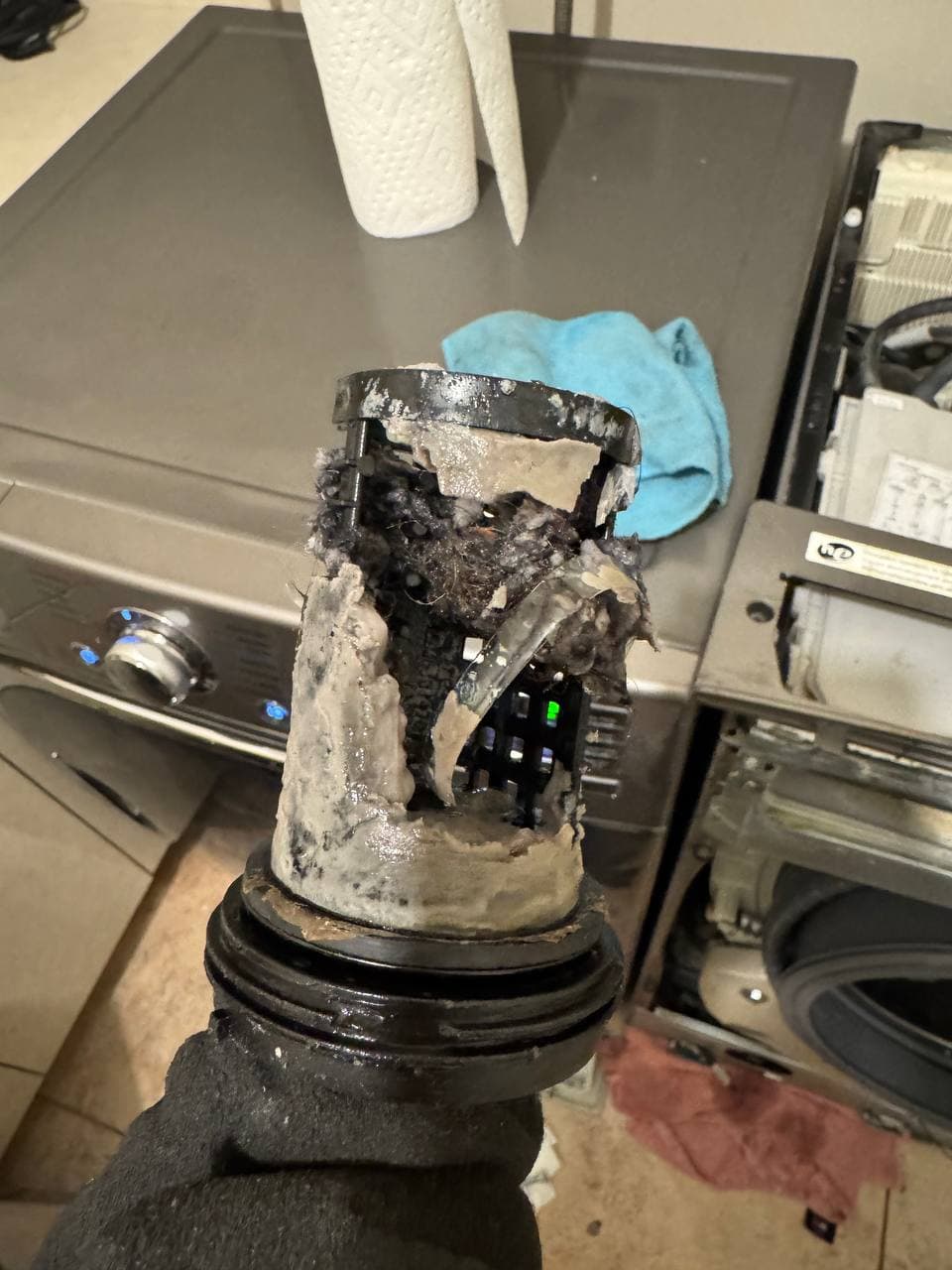 A dryer lint trap housing heavily clogged with compacted lint before cleaning