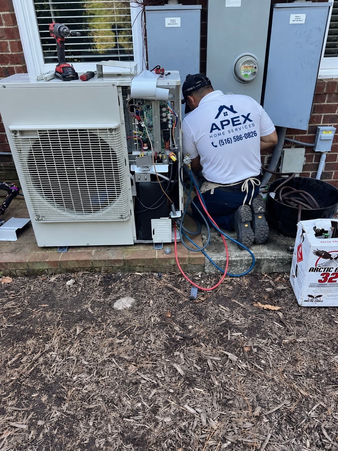 Apex technician connecting refrigerant gauges to an outdoor heat pump unit