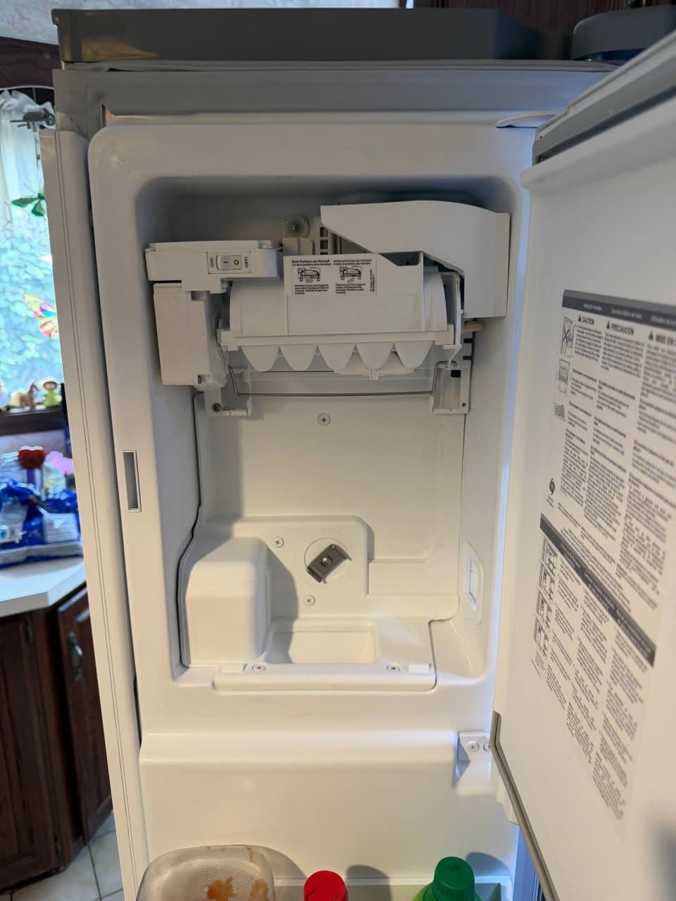 The new ice maker assembly installed in the refrigerator freezer door